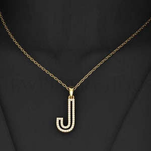 May include: A gold chain necklace with a pendant in the shape of the letter J. The pendant is encrusted with small, clear stones.