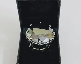 May include: A silver ring with a large, faceted, gray gemstone is displayed inside a black jewelry box. The ring has a unique, openwork design. The text "Namogems" is visible on the gemstone.