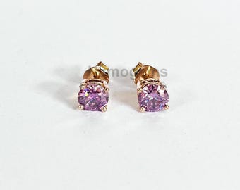 May include: A pair of rose gold stud earrings, each featuring a round, light purple gemstone. The earrings are set on a white background, showcasing their simple yet elegant design. The gemstones have a faceted cut, reflecting light.