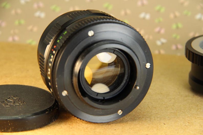 Pode incluir: Uma lente de c&acirc;mera preta com um anel prateado ao redor da borda. A lente tem uma grande abertura e uma profundidade de campo rasa.