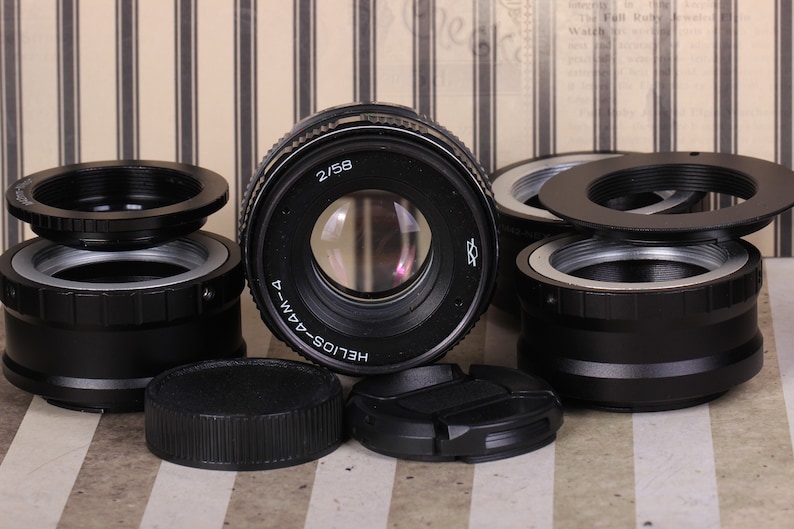 Pu&ograve; includere: Un obiettivo per fotocamera nero con la scritta "HELIOS-44M-4" e "2/58" stampata su di esso. L'obiettivo &egrave; circondato da diversi anelli e tappi in metallo nero.