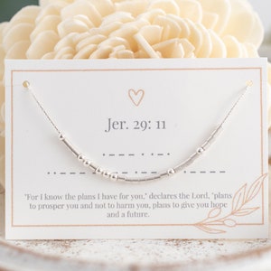 May include: A silver necklace with a small heart charm and the text "Jer. 29:11" on a white card. The card also includes the Bible verse "For I know the plans I have for you," declares the Lord, "plans to prosper you and not to harm you, plans to give you hope and a future."
