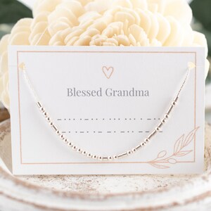 May include: A silver beaded necklace displayed on a white card with the text "Blessed Grandma" and a small heart.