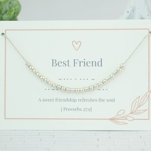 May include: A white card with a silver beaded necklace on it. The card says "Best Friend" and "A sweet friendship refreshes the soul [Proverbs 27:9]".