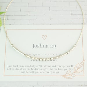 Könnte beinhalten: Eine silberne Perlenkette mit einer Karte, auf der "Josua 1,9" steht und der Vers "Habe ich dir nicht geboten? Sei stark und mutig! Fürchte dich nicht und verzage nicht, denn der Herr, dein Gott, ist mit dir, wohin du auch gehst."