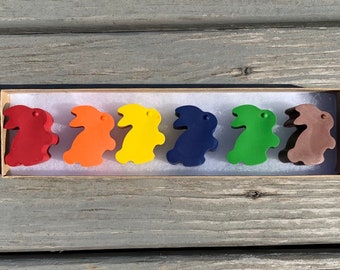 May include: Six colorful bunny-shaped crayons in a box. The crayons are red, orange, yellow, blue, green, and brown.