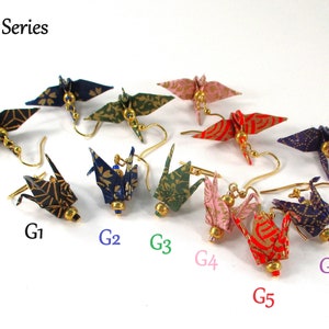 Op de afbeelding: Gold Series origami kraanvogel oorbellen in verschillende kleuren en patronen, waaronder zwart en goud, blauw en goud, groen en goud, roze en goud, rood en goud en paars en goud.