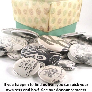 May include: A collection of round, colorful buttons with various designs and text, including "EH? DO I HEAR SOMEONE COMPLAINING". The buttons are displayed in a box with a green lid and a patterned bottom.