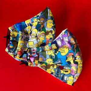 May include: A colorful fabric face mask featuring a pattern of various characters from the animated television show The Simpsons. The mask is made of a soft, breathable fabric and has a comfortable fit.