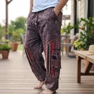 Puede incluir: Pantalones holgados de tela color granate con efecto lavado al ácido, con cintura elástica y cordón ajustable. Los pantalones incluyen bolsillos cargo laterales decorados con paneles verticales de patrones rojos, negros y blancos y motivos circulares.