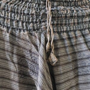 May include: Black and white striped pants with a drawstring waist. The pants are made of a soft, lightweight fabric and have a relaxed fit.