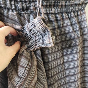 May include: Brown and white striped pants with a drawstring waist and elastic waistband. The pants are made of a soft, lightweight fabric.