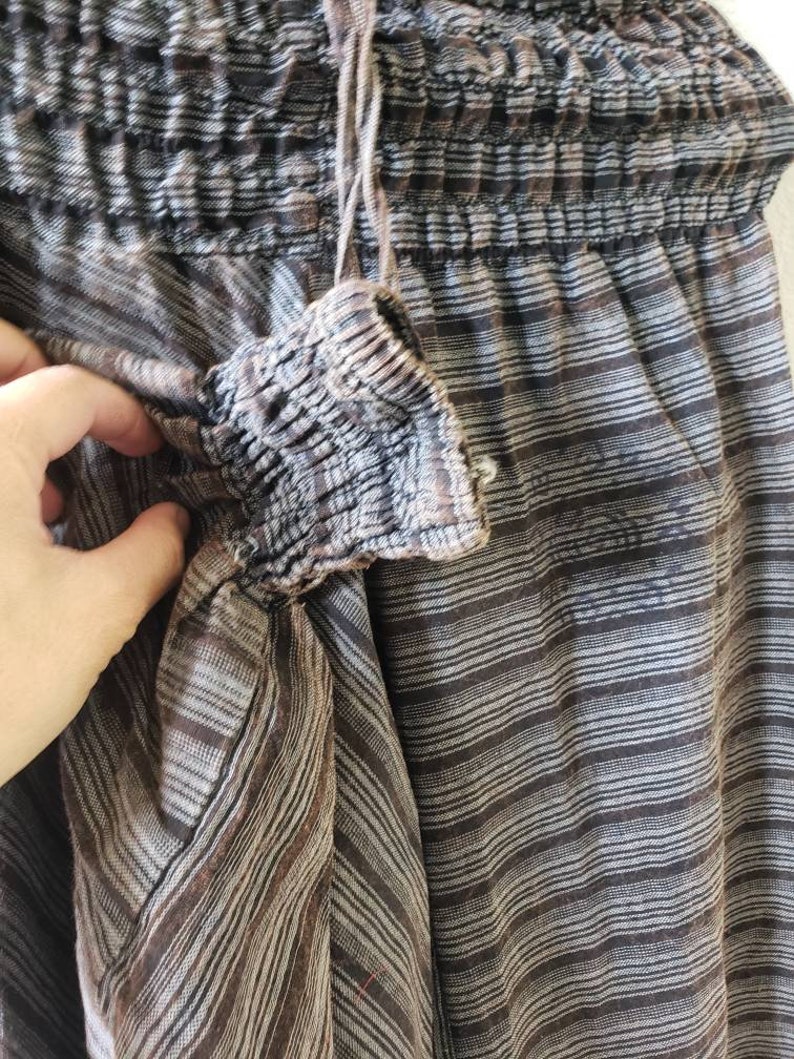 May include: Brown and white striped pants with a drawstring waist and elastic waistband. The pants are made of a soft, lightweight fabric.