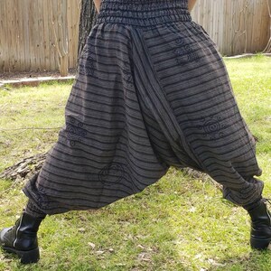 May include: Black and white striped pants with a wide leg and an elastic waistband. The pants have a unique design with a pattern of circles and swirls.