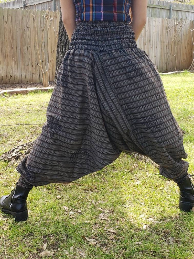 May include: Black and white striped pants with a wide leg and an elastic waistband. The pants have a unique design with a pattern of circles and swirls.
