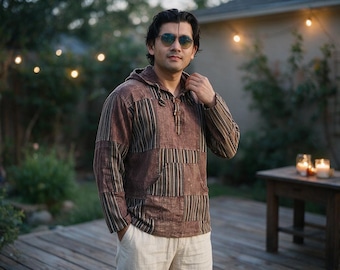May include: A long-sleeved hooded pullover shirt featuring a patchwork design of brown, tan, and black vertical stripes and solid brown panels. The garment includes a front kangaroo pocket, a drawstring hood, and a buttoned placket at the neckline.