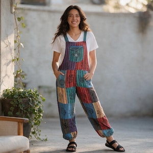 May include: A white short-sleeved t-shirt worn under multi-colored patchwork overalls featuring a variety of blue, red, and brown rectangular panels with black botanical prints, a front chest pocket, and elasticized cuffs at the ankles.