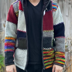 Pode incluir: Uma jaqueta com capuz de patchwork multicolorido com fecho de correr. A jaqueta é feita de uma variedade de tecidos de malha em tons de cinza, preto, vermelho, verde, amarelo e azul.