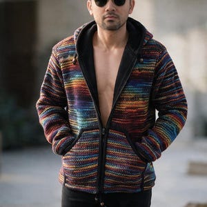 May include: A zip-up hoodie featuring a multi-colored knit pattern with horizontal stripes in shades of blue, orange, yellow, and purple. The garment includes a solid black interior lining, a hood with drawstrings, and two front pockets.