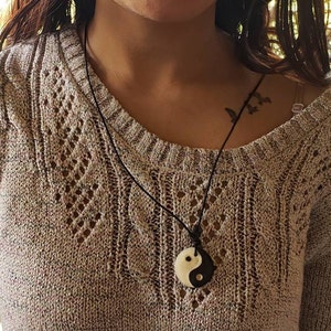 May include: A black cord necklace with a white and black yin yang pendant.