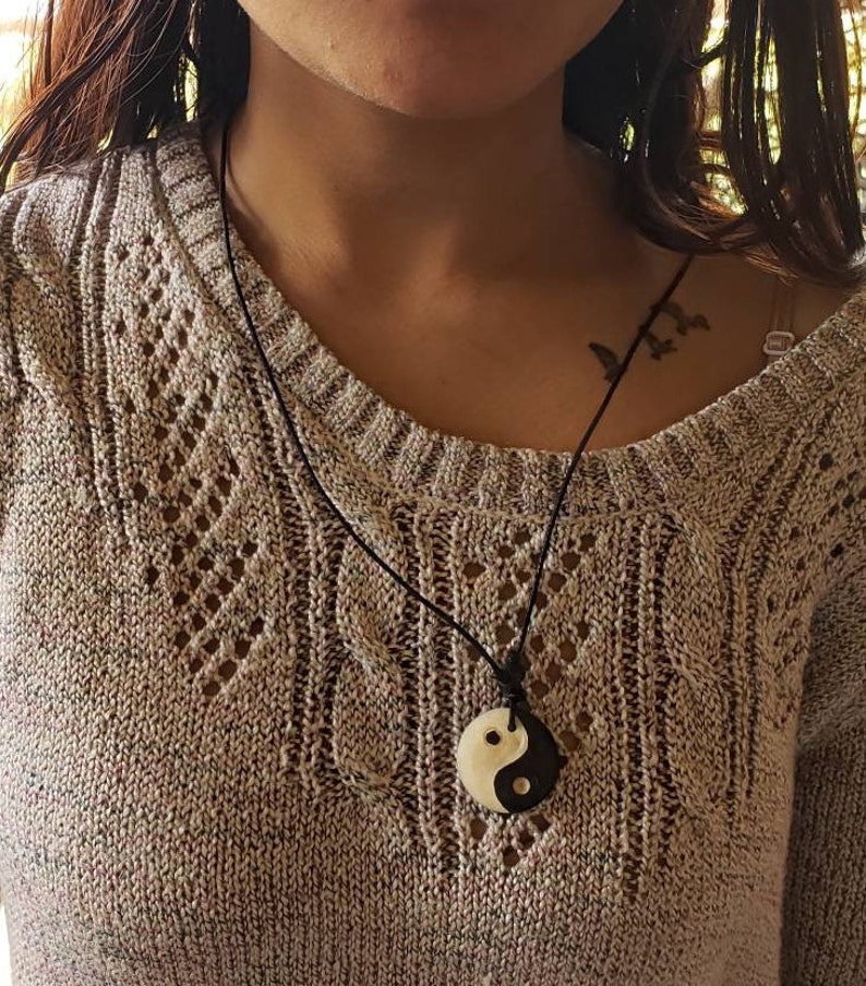 May include: A black cord necklace with a white and black yin yang pendant.