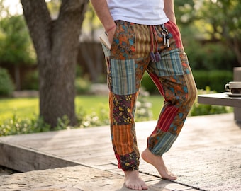 May include: Patchwork joggers featuring a variety of colourful fabric panels in shades of orange, blue, red, and brown. These trousers include an elastic waistband with a drawstring, side pockets, and elasticated cuffs at the ankles for a relaxed fit.