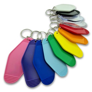 May include: A set of ten colourful keychains in the shape of a hotel room key. The keychains are arranged in a rainbow pattern, starting with pink and ending with yellow. Each keychain has a silver metal ring.