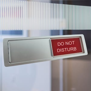 May include: A silver door sign with a red sliding panel that says "DO NOT DISTURB" in white text.