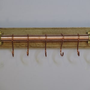 Copper kitchen utensil/pan hanging rail mounted on a wooden back board with handmade solid copper hanging hooks.