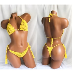 May include: A bright yellow crochet bikini set. The top is a triangle style with halter straps. The bottoms are a thong style with tassel ties on each side. The bikini is displayed on a mannequin.