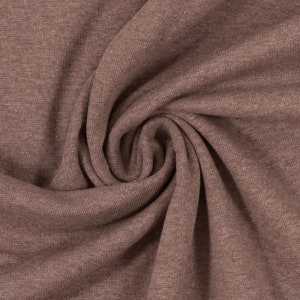 Könnte beinhalten: Nahaufnahme eines weichen, braunen Stoffes mit einer strukturierten Oberfläche. Der Stoff ist gefaltet und drapiert und zeigt seine Textur und seinen Fall.