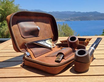May include: A brown leather tobacco pipe case with a zipper, open to reveal pockets and a small knife. Two wooden tobacco pipes and a small wooden tray are also visible. The text "Your doctor or" is partially visible.