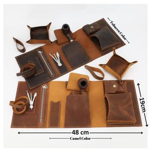 May include: Two leather tobacco pipe rolls in tobacco and camel colors, each featuring pockets, a zippered compartment, a pipe holder, and metal tools. The rolls measure 48 cm by 19 cm. Included are two matching leather valet trays and leather loops.