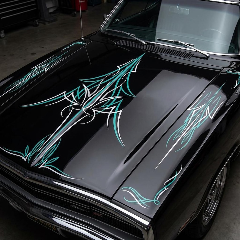 May include: Close-up of a black car hood with custom pinstriping. The design features teal and white lines and shapes, creating a dynamic and artistic pattern. The hood is glossy, reflecting the surrounding environment.