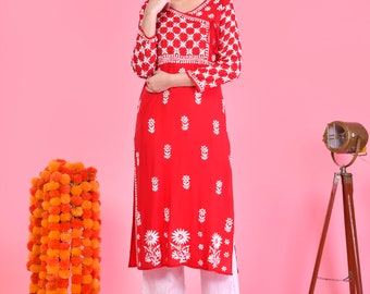 Puede incluir: Una kurta de manga larga roja y blanca con bordados florales blancos. La kurta tiene un escote en V y un cierre de nudo lateral. La modelo lleva pantalones blancos y sandalias.