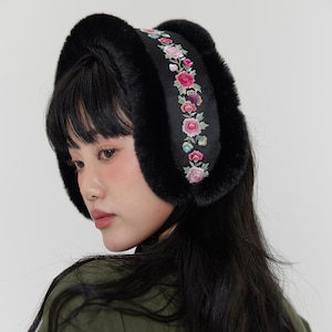 Op de afbeelding: Zwarte imitatiebont oorbeschermers met een bloemen geborduurde band. De band heeft roze, rode en blauwe bloemen met groene bladeren. De oorbeschermers worden over de oren gedragen en zijn verbonden door een zwarte band.