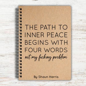 May include: A spiral-bound notebook with a tan kraft paper cover featuring black text that reads: THE PATH TO INNER PEACE BEGINS WITH FOUR WORDS not my fucking problem By Shaun Harris. The notebook has a metal coil spine on the left side.