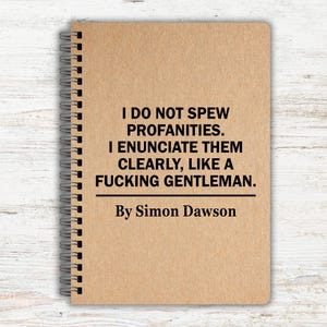 May include: A spiral-bound notebook with a tan cover. The cover features the text: "I DO NOT SPEW PROFANITIES. I ENUNCIATE THEM CLEARLY, LIKE A FUCKING GENTLEMAN. By Simon Dawson."