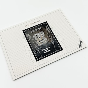 May include: A sketchbook featuring a black and white illustration of a nude figure. The cover displays the text "SHI BAKU" and "VORLAGEN MIT FIGUREN". The sketchbook is on a white surface with a grid pattern.