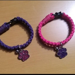 Puede incluir: Dos collares trenzados para mascotas, uno morado y otro rosa. Cada collar tiene un cierre de plástico negro, una campana plateada y un dije en forma de pata con purpurina. Diseñados para mascotas pequeñas.