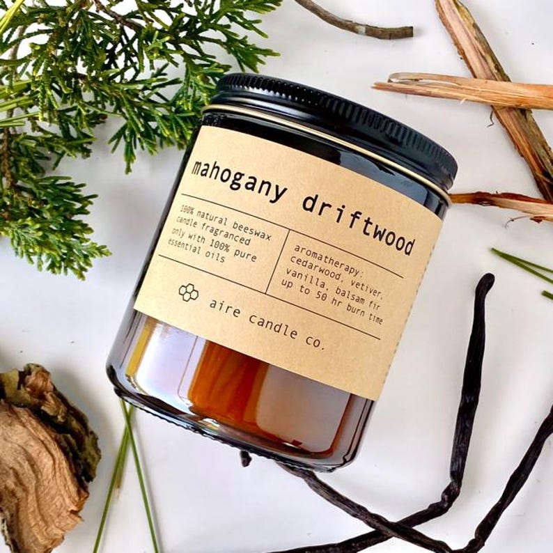 A lay-flat image of the Mahogany Driftwood candle with scent notes surrounding it. These scent notes are Cedarwood, Balsam Fir, Vanilla and Vetiver.