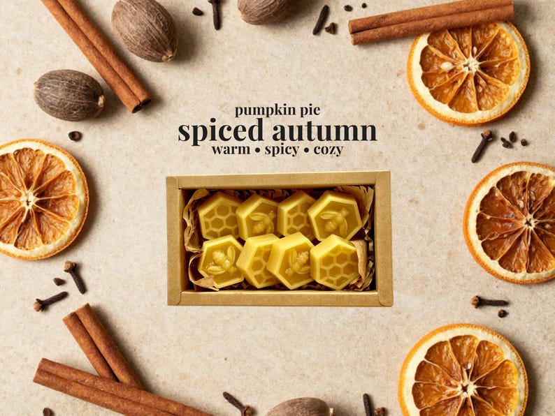 May include: A rectangular cardboard box containing eight yellow hexagonal wax melts, each embossed with a bee or honeycomb pattern. The text "pumpkin pie spiced autumn warm &bull; spicy &bull; cozy" is printed above the box, surrounded by cinnamon sticks, dried orange slices, nutmeg, and cloves.