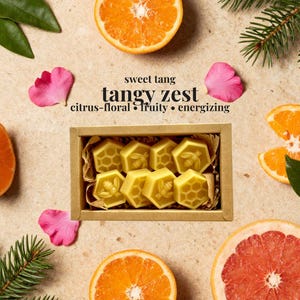 May include: A rectangular cardboard box containing six yellow wax melts shaped like hexagons, featuring embossed bee and honeycomb patterns. The text "sweet tang", "tangy zest", and "citrus-floral &bull; fruity &bull; energizing" is printed above the box.
