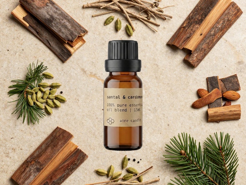 Santal & Cardamom 100% pure essential oil blend by Aire Candle Co. in a 15 ml amber glass bottle, styled with smooth sandalwood pieces, green cardamom pods, cedarwood bark, vetiver and fresh pine sprigs. This warm, woodsy-spiced blend combines creamy sandalwood depth with subtle aromatic spice—perfect for creating a cozy, grounding, and sophisticated home ambiance.