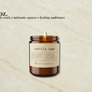 May include: An 8 oz. single wick candle in an amber glass jar with a beige label reading vanilla sage, 100% natural beeswax, and aire candle co. The candle features a lit wick and lists aromatherapy notes of vanilla, sage, pine, and lavender.