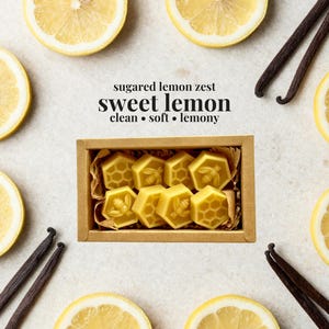 May include: A rectangular cardboard box containing eight yellow hexagonal wax melts, each embossed with bee or honeycomb patterns. The text above reads: sugared lemon zest, sweet lemon, clean, soft, lemony. The box is surrounded by lemon slices and vanilla beans.