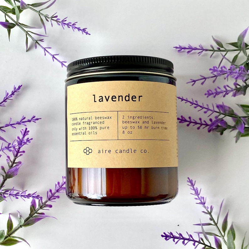 K&ouml;nnte beinhalten: Eine braune Glas-Kerze mit schwarzem Deckel, beschriftet mit "Lavendel". Das Etikett gibt an, dass die Kerze aus Bienenwachs und &auml;therischen Lavendel&ouml;len hergestellt wurde, mit einer Brenndauer von bis zu 50 Stunden. Die Kerze ist 227g.