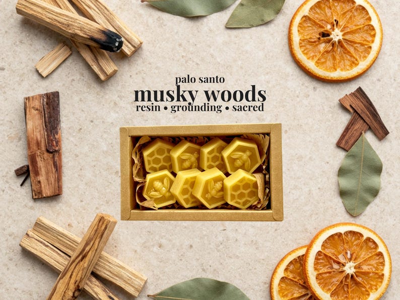 May include: A rectangular cardboard box containing eight yellow beeswax melts shaped like hexagons, featuring bee and honeycomb patterns. The text reads: palo santo musky woods resin &bull; grounding &bull; sacred. Surrounding the box are palo santo sticks, dried orange slices, and green leaves.