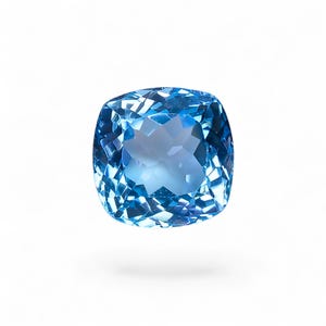 May include: A cushion-cut gemstone with a vibrant sky-blue color and a faceted surface that reflects light. The stone features a square shape with rounded corners and a transparent, crystalline appearance, showcasing intricate geometric patterns.