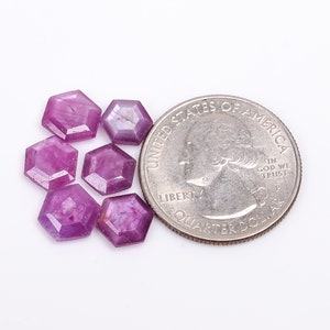 Peut inclure: Six petites pierres précieuses violettes facettées, chacune en forme d'hexagone, sont disposées en grappe. Les pierres précieuses sont à peu près de la taille d'une pièce de 25 cents américaine.